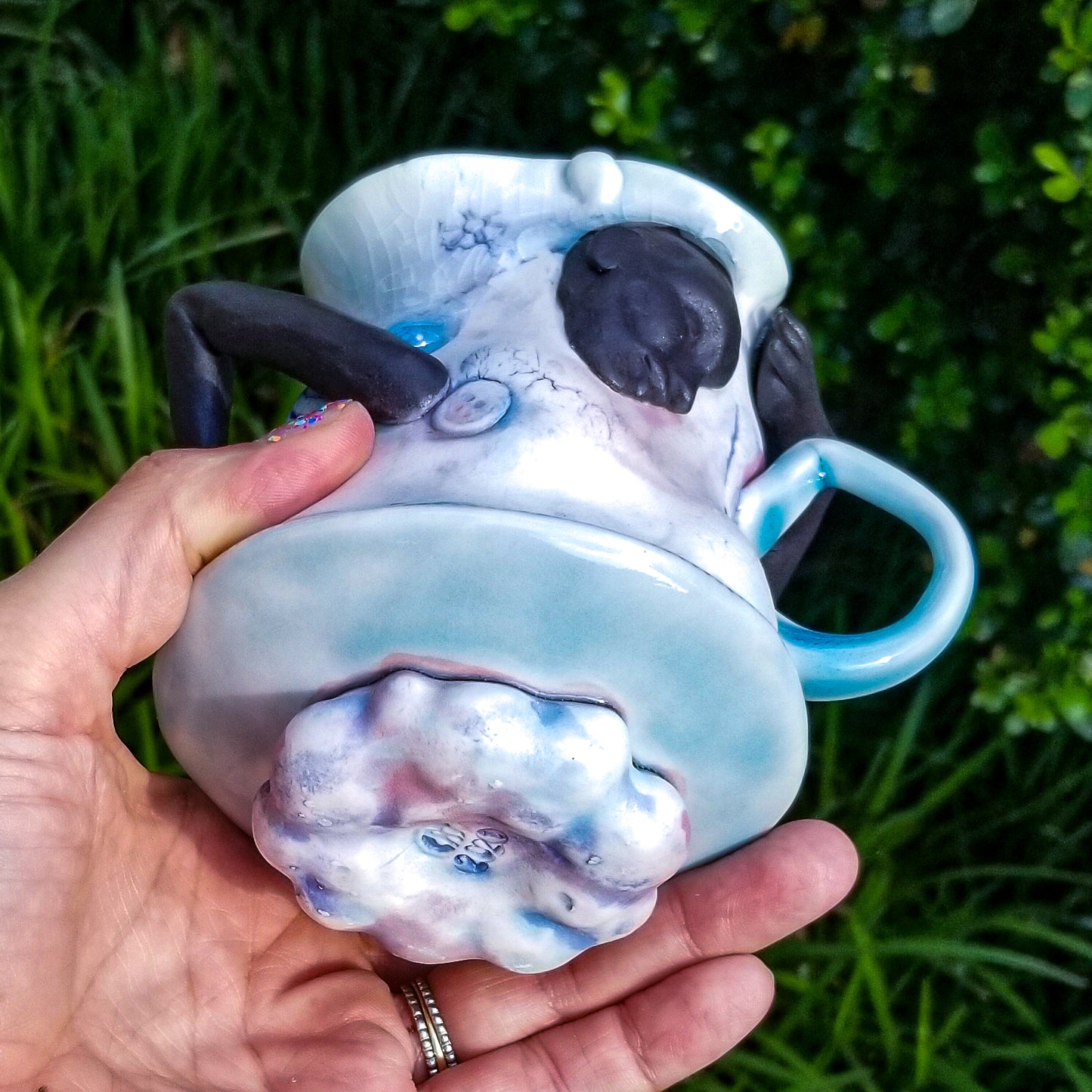 Bottom detail of handmade porcelain mug with figurative sculptural elements