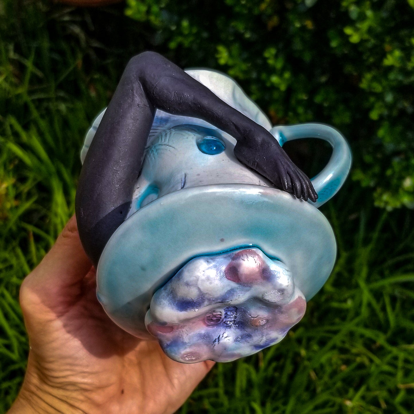 Bottom detail of handmade porcelain mug with figurative sculptural elements