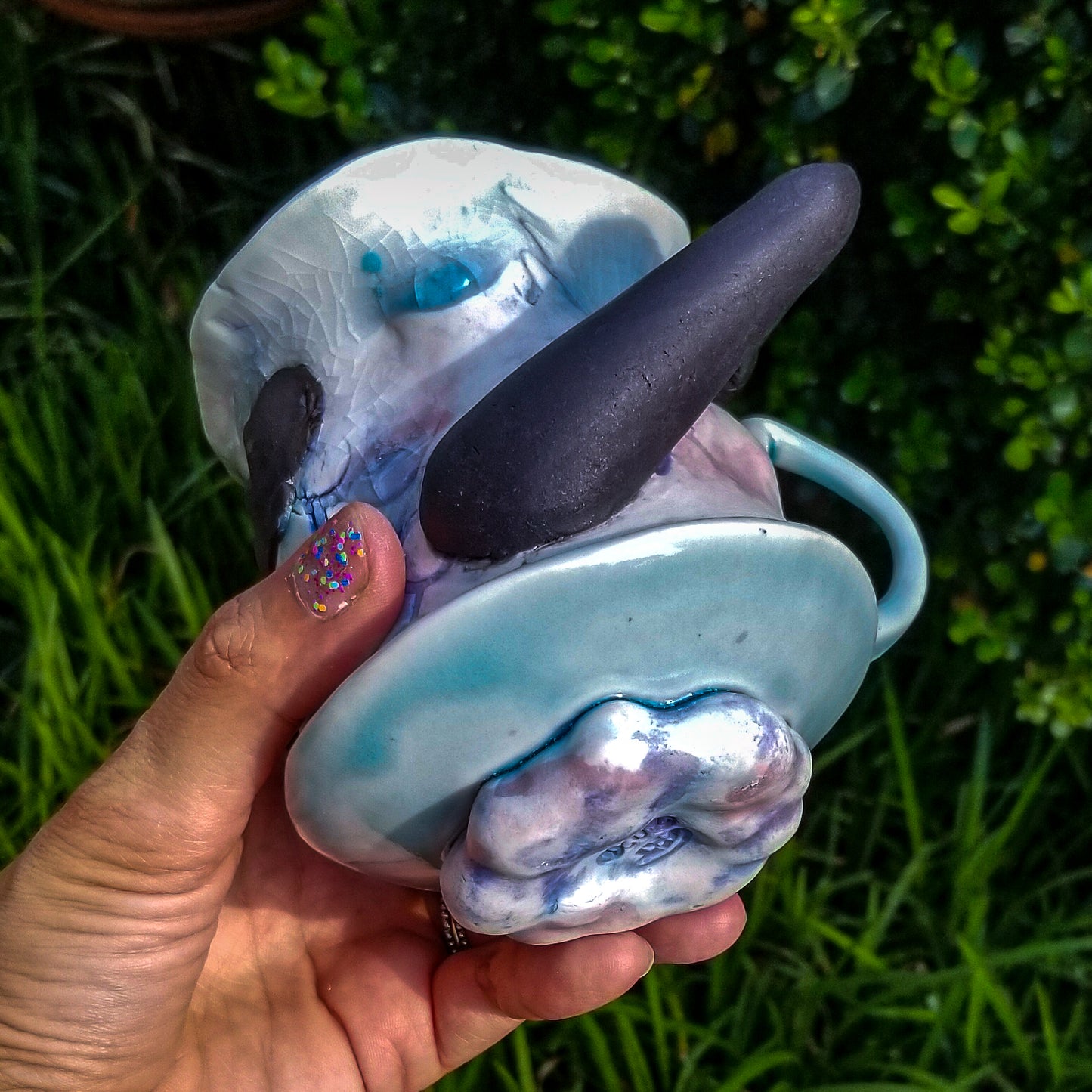 Bottom detail of handmade porcelain mug with figurative sculptural elements