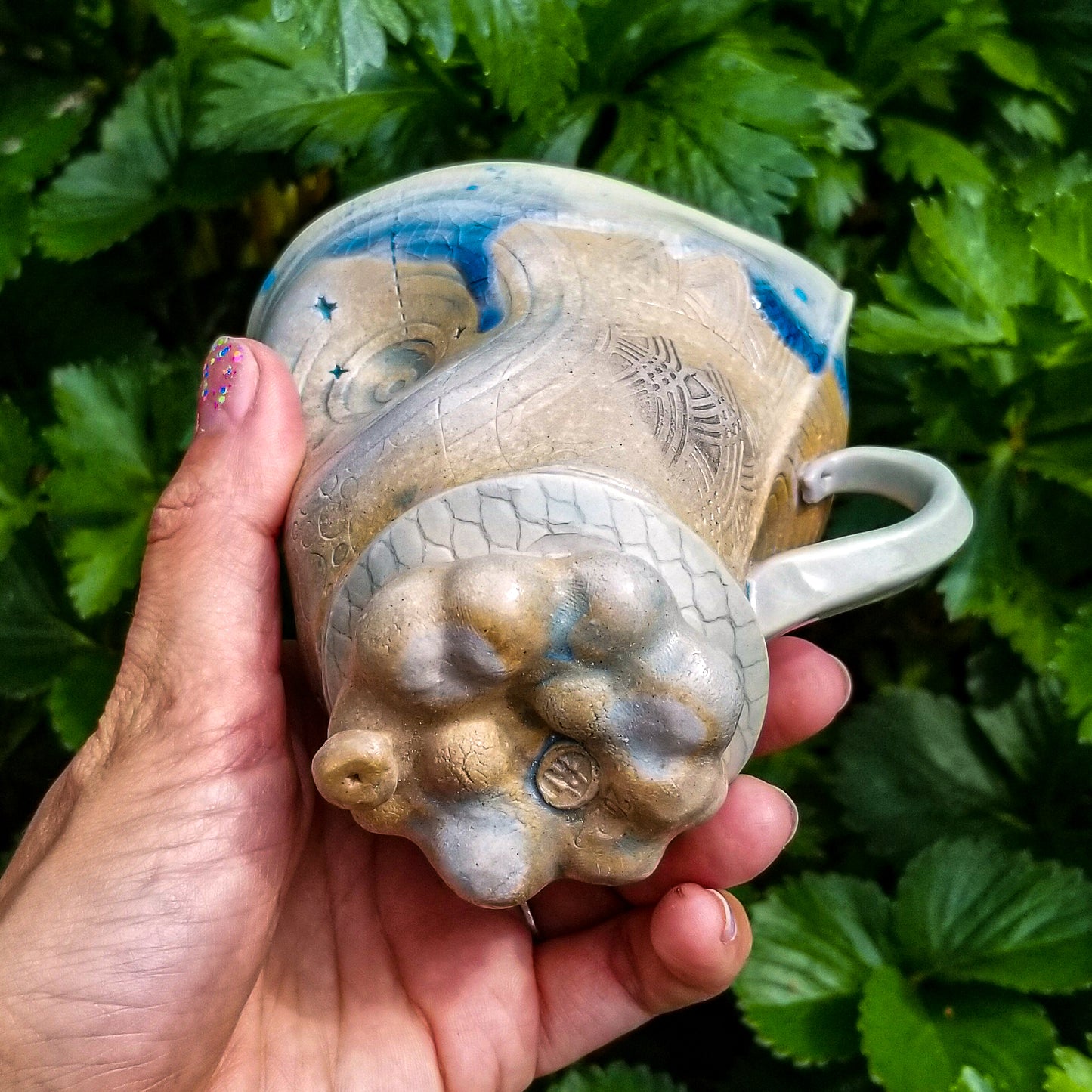 Bottom detail of handmade stoneware ceramic soda fired mug blue color with pressed textures
