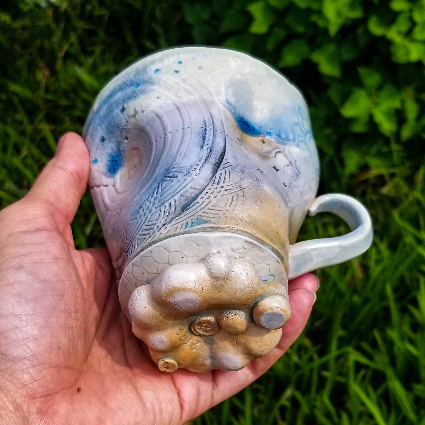 Bottom detail of handmade stoneware ceramic soda fired mug blue color with pressed textures