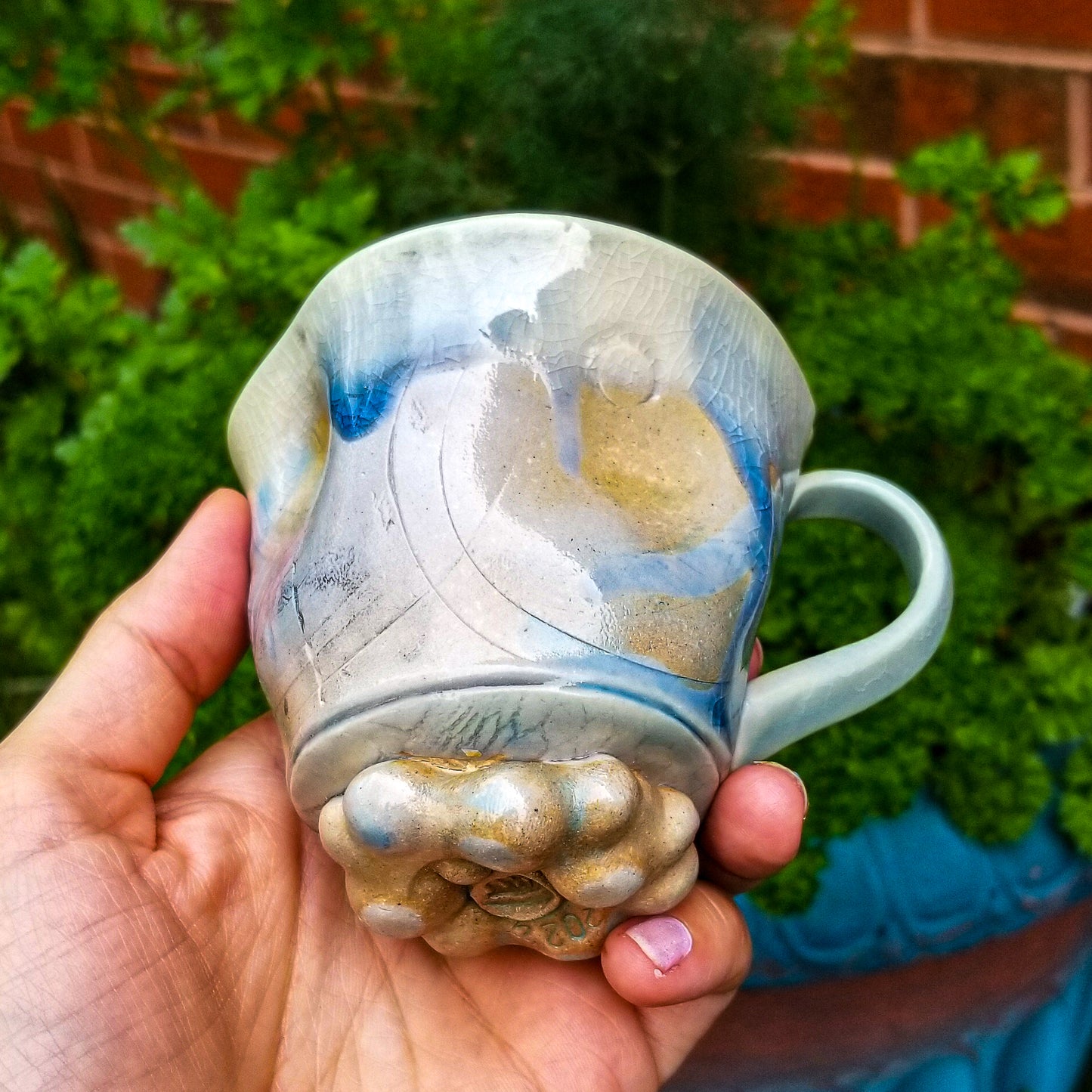 Bottom detail of handmade stoneware ceramic soda fired mug blue color with pressed textures