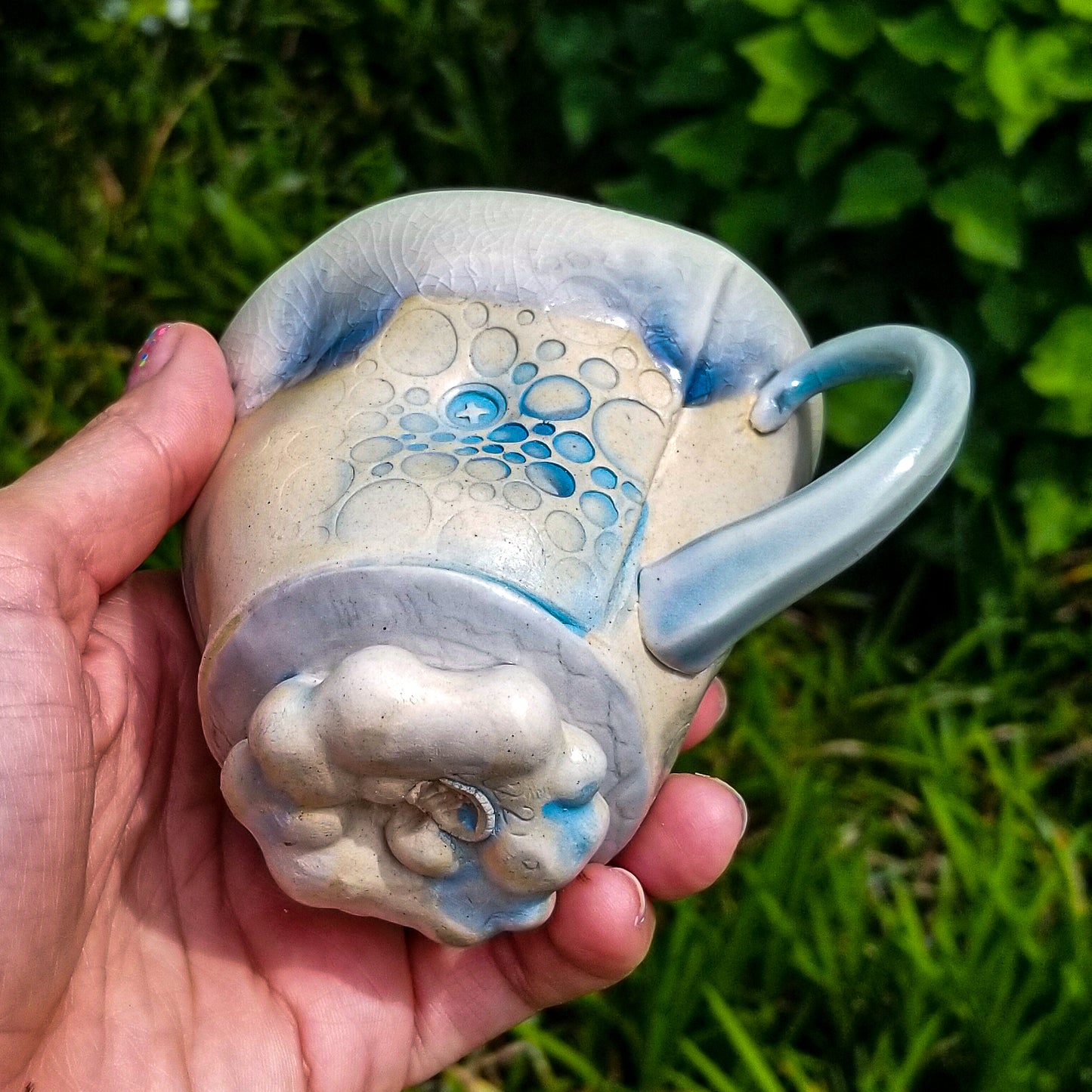Bottom detail of handmade stoneware ceramic soda fired mug blue color with pressed textures