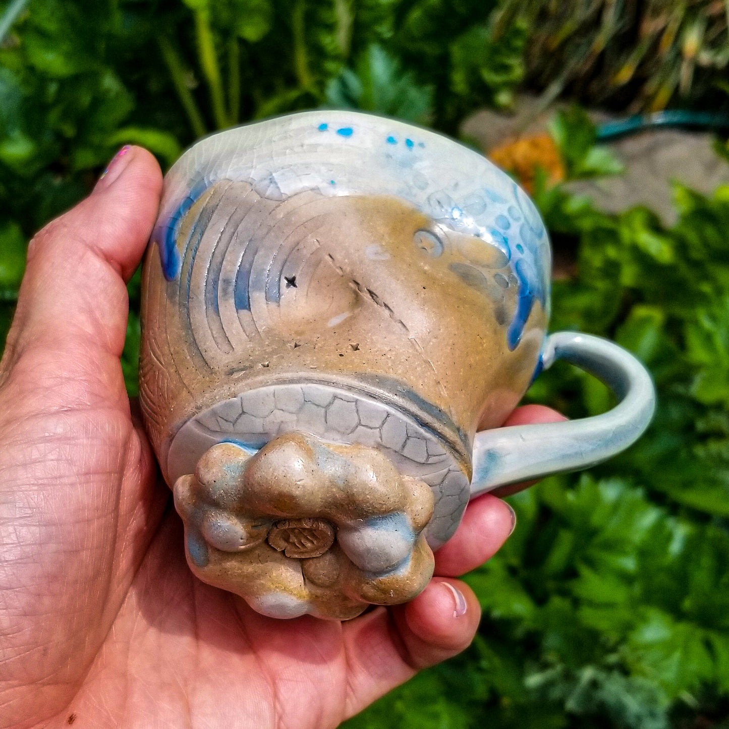 Bottom detail of handmade stoneware ceramic soda fired mug blue color with pressed textures