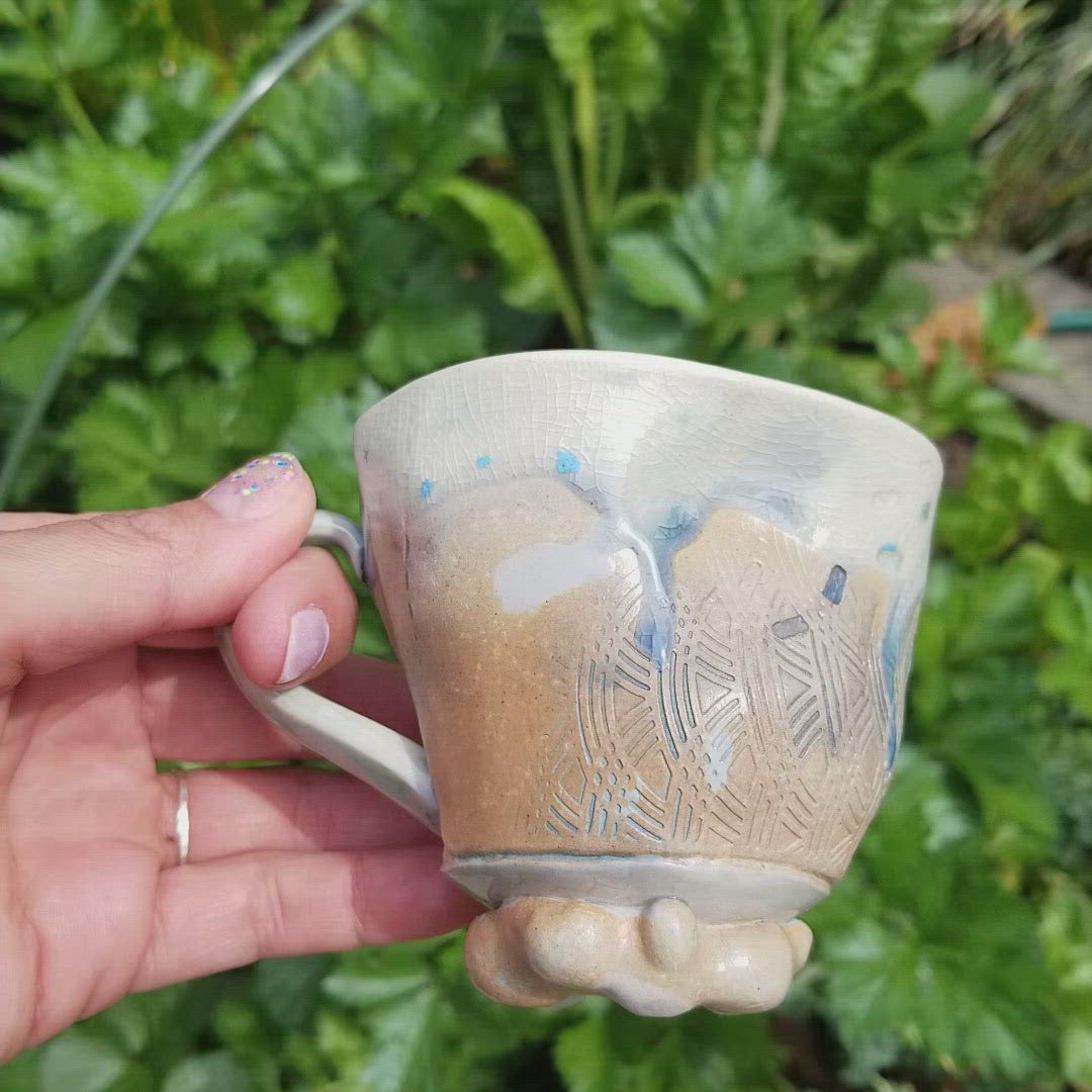 Video of handmade stoneware ceramic soda fired mug blue color with pressed textures