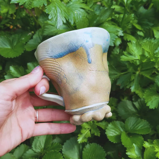 Video of handmade stoneware ceramic soda fired mug blue color with pressed textures