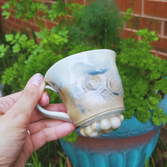 Video of handmade stoneware ceramic soda fired mug blue color with pressed textures