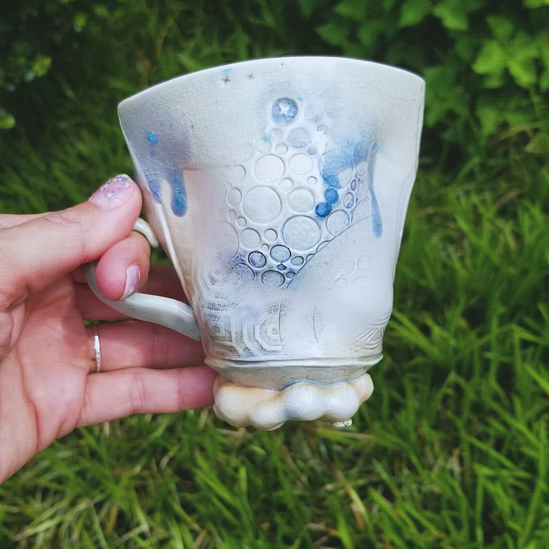 Video of handmade stoneware ceramic soda fired mug blue color with pressed textures