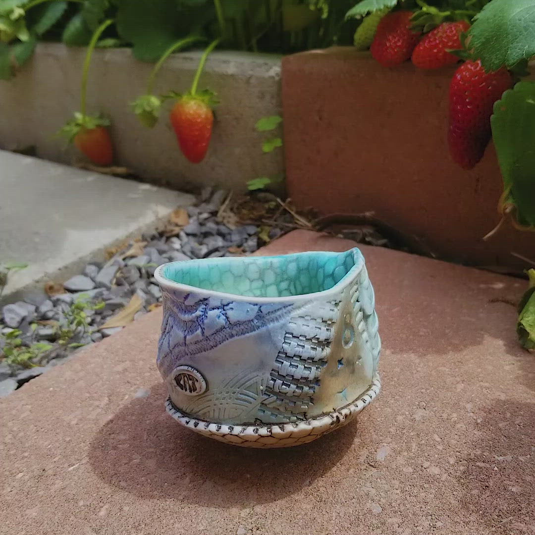 Video of spinning handmade stoneware ceramic soda fired cup blue color with pressed textures