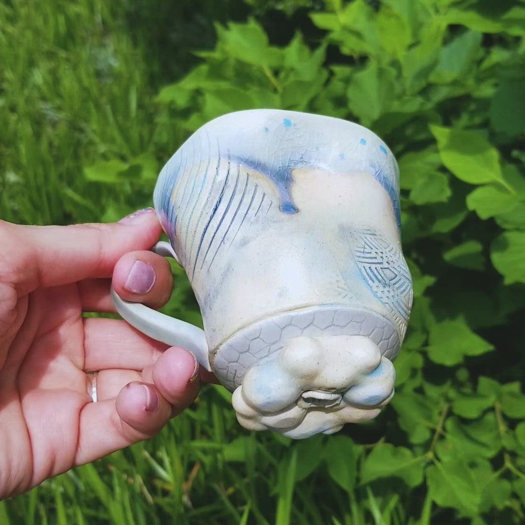 Video of handmade stoneware ceramic soda fired mug blue color with pressed textures
