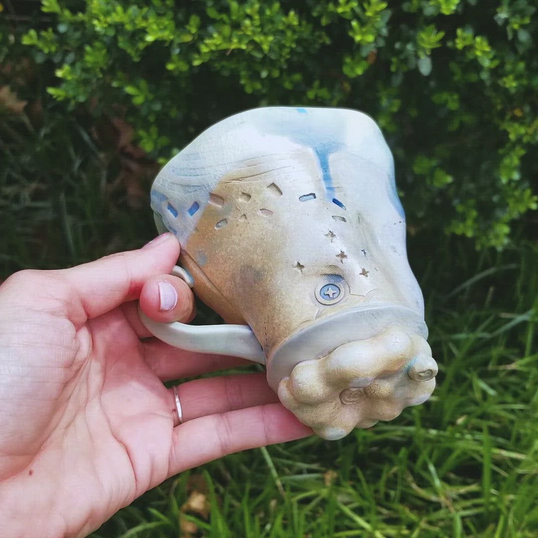 Video of handmade stoneware ceramic soda fired mug blue color with pressed textures