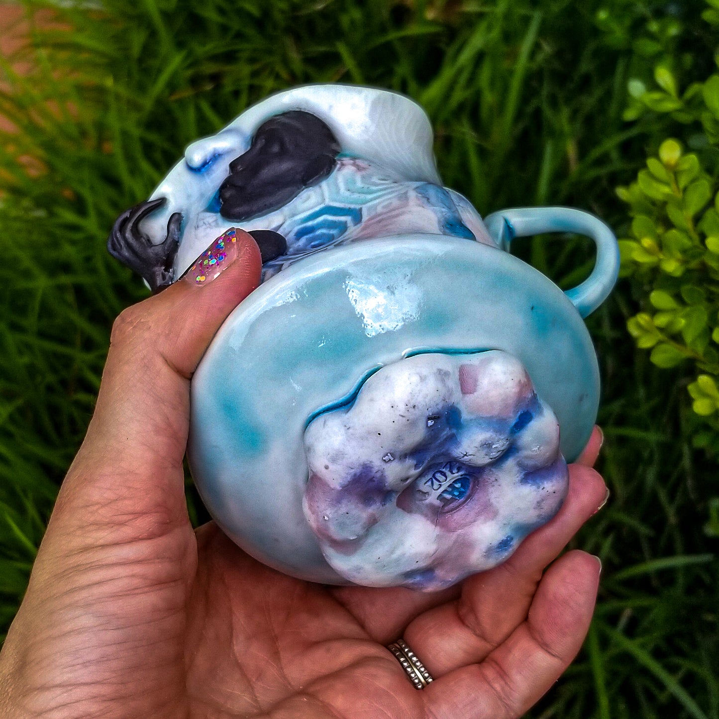 Bottom detail of handmade porcelain mug with figurative sculptural elements