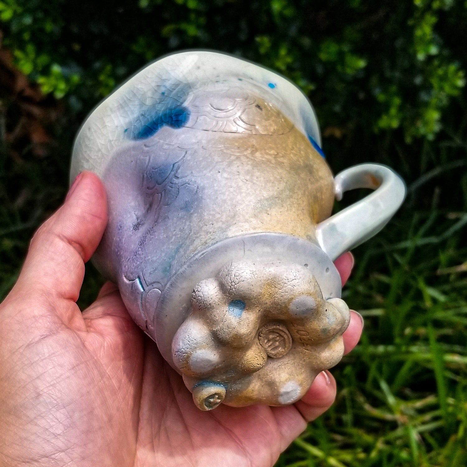 Bottom detail of handmade stoneware ceramic soda fired mug blue color with pressed textures