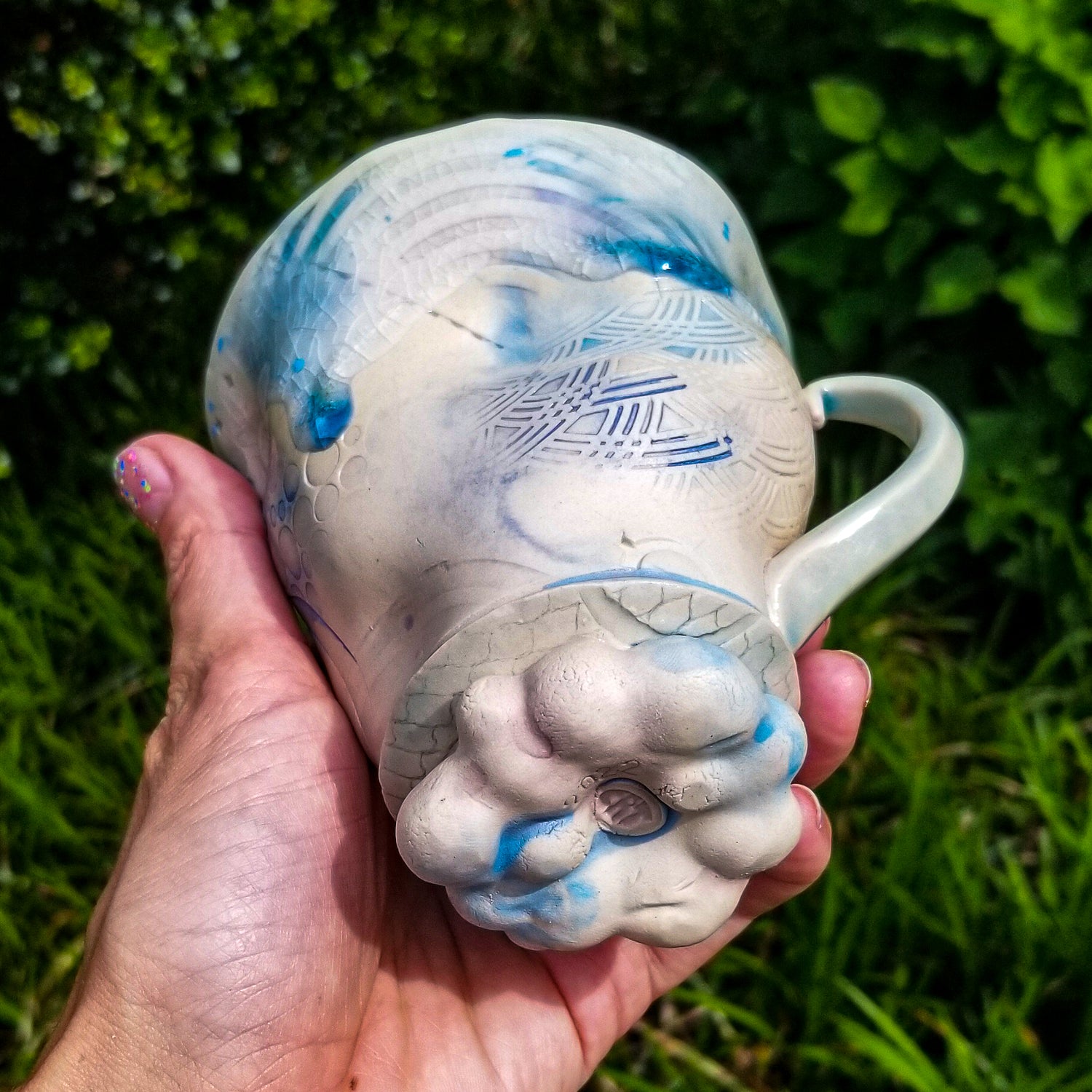 Bottom detail of handmade stoneware ceramic mug blue color with pressed textures