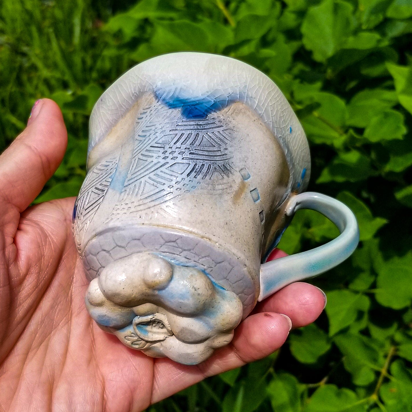 Bottom detail of handmade stoneware ceramic soda fired mug blue color with pressed textures