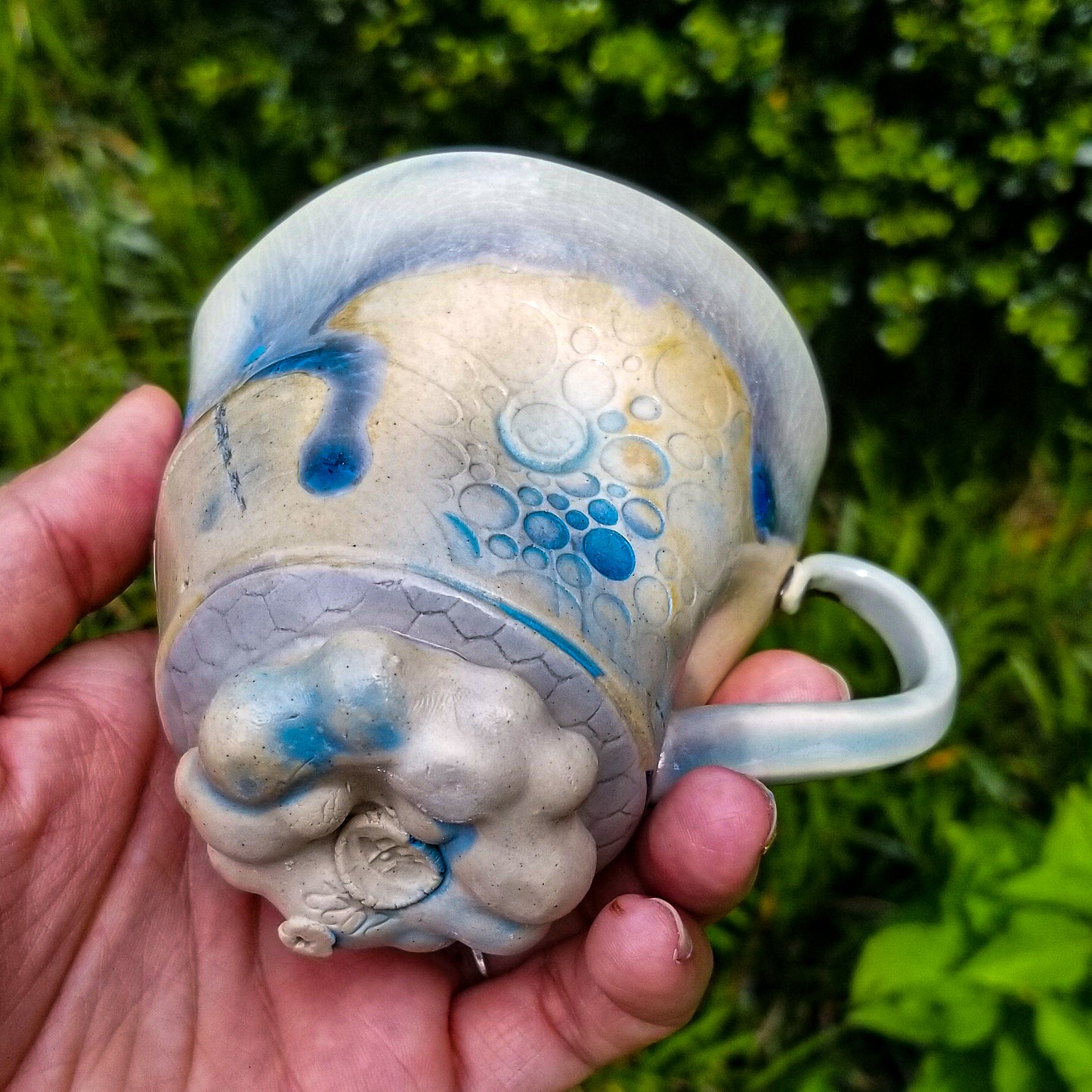 Bottom detail of handmade stoneware ceramic soda fired mug blue color with pressed textures