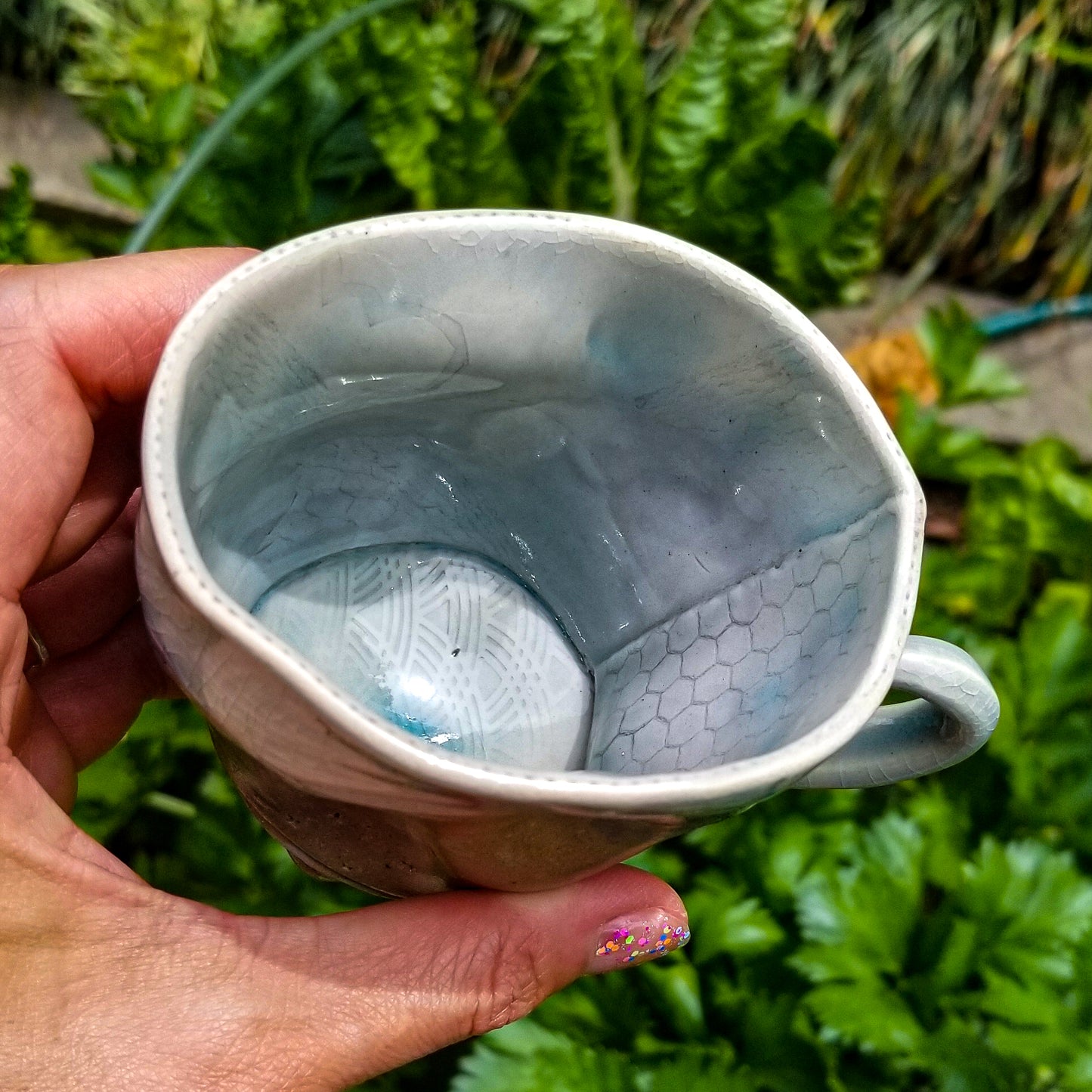 Inside detail of handmade stoneware ceramic soda fired mug blue color with pressed textures