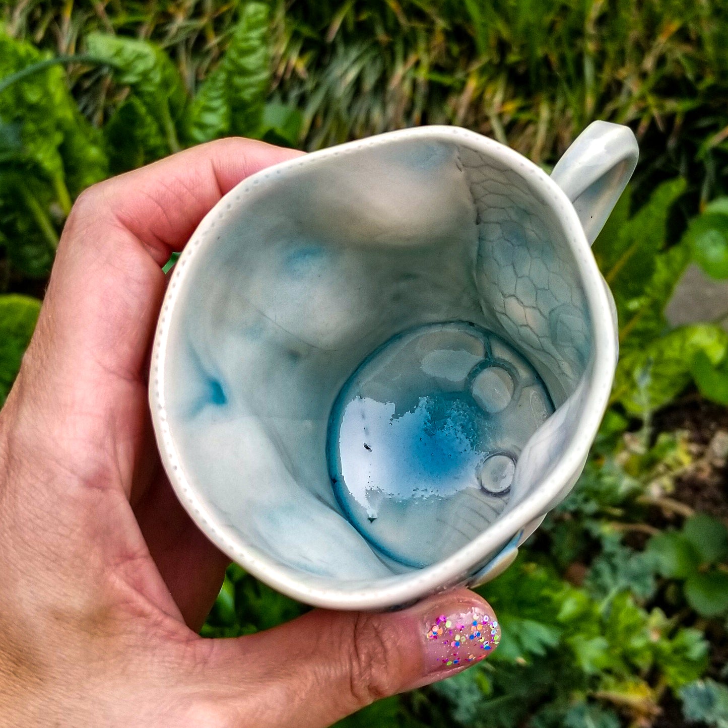 Inside detail of handmade stoneware ceramic mug blue color with pressed textures